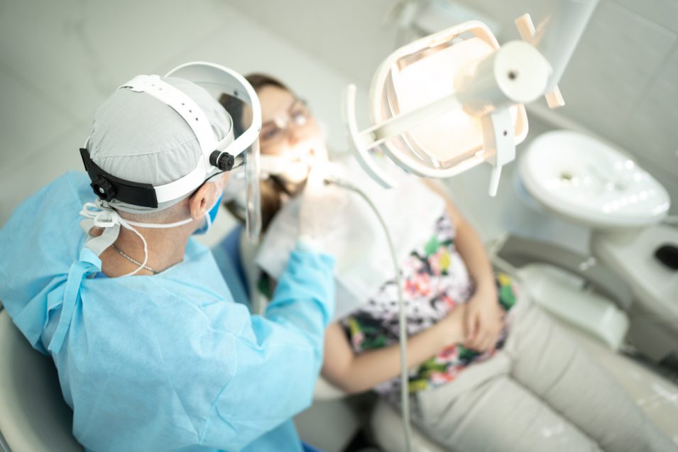 Senior dentist examining the teeth of a young woman