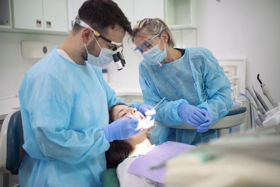 Dentist examining patient mouth in medical clinic.