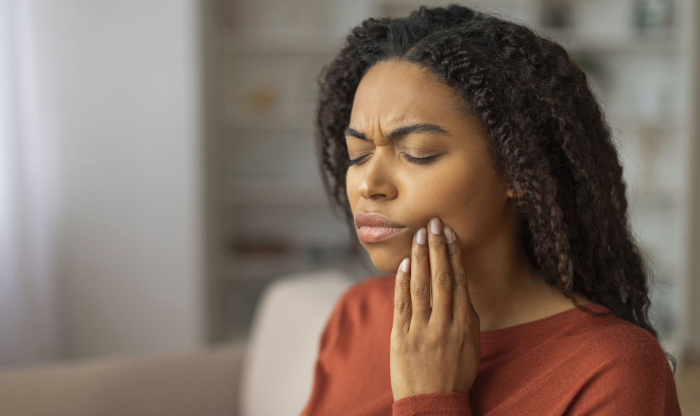 One-Sided Tooth Pain: Sinus vs Dental Causes A person holding one side of the face with tooth pain, illustrating how sinusitis can cause unilateral upper tooth discomfort.