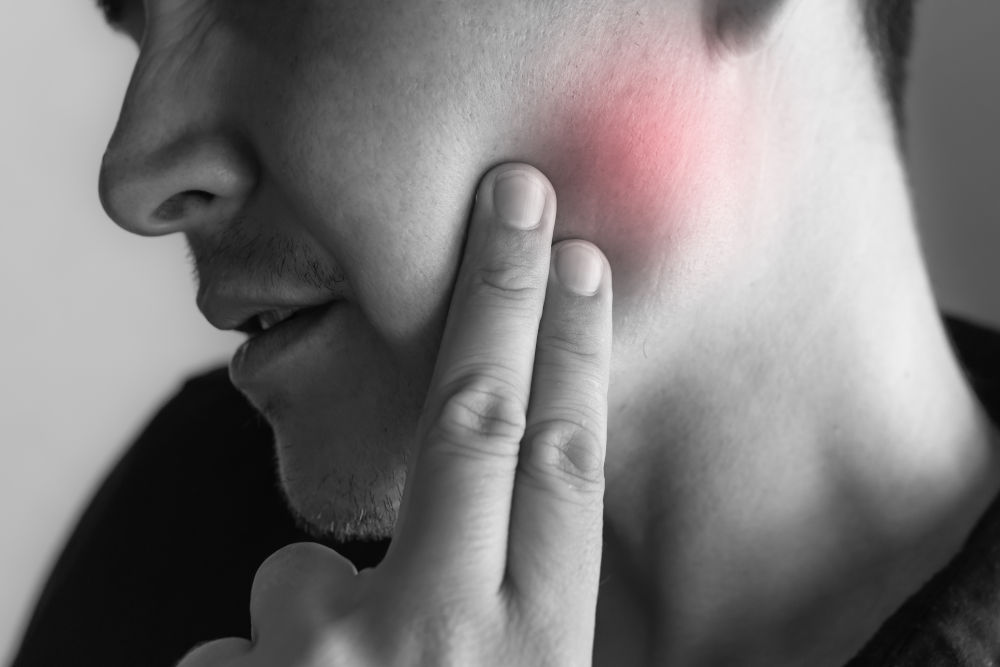 Facial Pressure and Upper Tooth Pain A person experiencing facial discomfort and upper tooth pain, consistent with sinus pressure affecting the maxillary sinus area.